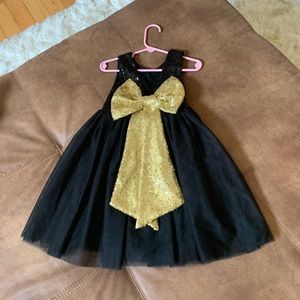 A cute little sequins black dress with a gold sequins bow. Size 2t-3t.